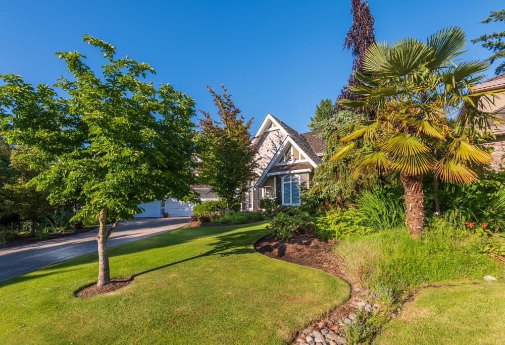 Crew member mowing crisp stripes into a large residential lawn